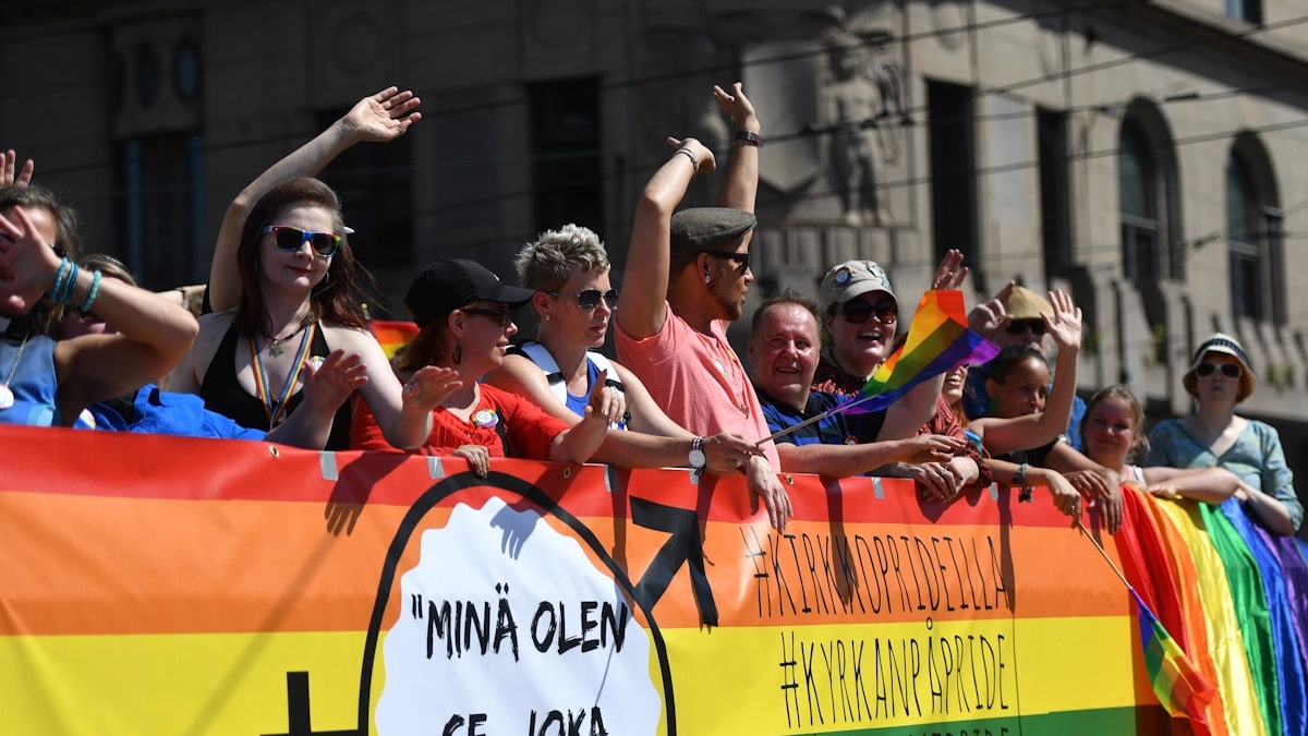 A vibrant LGBTQ pride parade in the city center of Helsinki, with colorful flags, balloons, and joyful people marching together in celebration of diversity, equality, and inclusion.